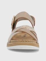 Sandalia de plataforma baja color beige con tiras cruzadas, una de ellas con acabado texturizado brillante. Presenta una tira ajustable con hebilla decorativa y cierre de velcro, sobre una suela de estilo yute con base de poliuretano.