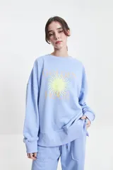 Buzo de felpa color marrón con estampa frontal en rosa, cuello redondo y hombros caídos.