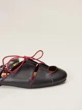 Sandalias planas tipo slingback de cuero marrón, con diseño delantero calado, cierre de cordones y tira trasera ajustable con hebilla.