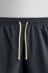 Short de baño rojo de tejido técnico ligero y elástico, con cintura elástica ajustable mediante cordón blanco y aberturas laterales en las perneras.