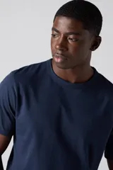 Remera de algodón de corte estándar con cuello redondo y manga corta. Presenta un diseño liso en color azul marino con un pequeño logo bordado en el pecho.