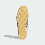 Championes Adidas modelo Japan, reedición de diseño clásico de 1964. Presentan un empeine de piel perforada en color crema con las icónicas tres bandas laterales en tono marrón. Incluyen refuerzos de gamuza en la puntera y el talón, junto con una suela de goma en tono amarillento que aporta un estilo vintage.