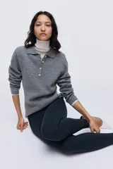 Buzo de punto suave color gris, con cuello clásico estilo polo, tapeta con botones frontales, mangas largas y hombreras.