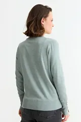 Sweater de punto fino en color verde menta, con cuello redondo, mangas largas y puños acanalados con detalle de botones metálicos laterales.