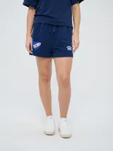 Bermuda deportiva azul marino Umbro del Club Nacional de Football, con bolsillos laterales, cordón ajustable en la cintura y detalles con líneas laterales. Incluye el escudo del club y el logo de la marca bordados.