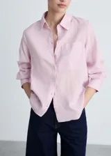 Camisa de corte recto confeccionada en una mezcla de lino y algodón, color rosado. Presenta cuello camisero, cierre frontal de botones, bolsillo de parche en el pecho y mangas largas con puños abotonados.
