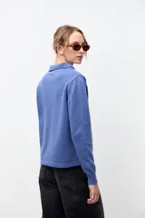 Cardigan de punto color azul con cuello polo y cierre frontal de botones. Presenta mangas largas con puños acanalados y un corte recto.