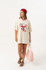 Bolso tipo tote bag de tela color crudo con estampado de letras en color naranja. Tiene asas de hombro de tela con diseño de espiga y un bolsillo frontal.