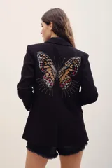 Saco sastrero negro de corte clásico con solapas, manga larga y gran diseño bordado de mariposa en la espalda con detalles metalizados.