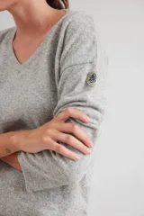 Buzo de escote en V y manga larga, confeccionado en lana lambswool. Presenta un diseño básico con detalle de raya en contratono en una de las mangas, puños y ruedo en color contrastante, y pin metálico de la marca aplicado en la manga.