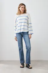 Sweater de punto color blanco con rayas horizontales azules, de corte holgado y mangas largas acampanadas.