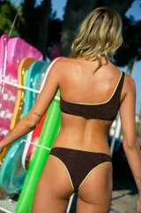 Conjunto de bikini marrón oscuro brillante con ribetes verde neón. El corpiño es un top de un solo hombro con hebilla metálica. La bombacha es vedetina.