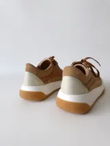 Zapatillas deportivas de cuero color camel con cordones marrones y suela blanca.