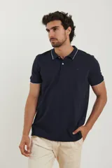 Chomba azul marino de piqué con cuello clásico y tapeta de dos botones. Detalles de ribete blanco en cuello y mangas.