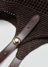 Bolso tipo tote color marrón con diseño de tejido calado de fibra natural, doble asa larga de hombro con detalle de hebilla ajustable y aplique metálico dorado, e incluye un bolso interno de tela con cierre de cremallera.