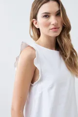 Vestido corto blanco de lino, sin mangas, con volados en los hombros y escote redondo.