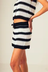 Short tejido a crochet con rayas horizontales blancas y negras, con cintura elástica y cordón ajustable.