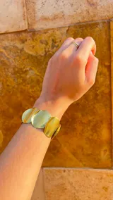 Brazalete rígido dorado con apliques circulares texturizados.