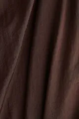 Pantalón baggy de satén color marrón, con cintura elástica y bajos ajustados con elástico, creando un efecto de volumen en las piernas.