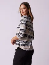 Remera de algodón con estampado floral y de rayas horizontales en tonos azules, negros y beige. Presenta escote redondo a la base y mangas tres cuartos.
