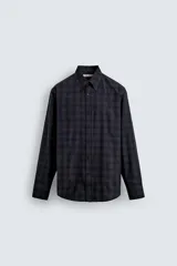 Camisa de corte regular fit confeccionada en tejido de algodón con estampado de cuadros oscuros. Presenta cuello abotonado, manga larga con puños abotonados y cierre frontal con botones.