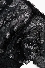Pack de dos bombachas tipo brazilian de tiro bajo en color negro, confeccionadas completamente en encaje con diseño floral. Presentan cintura en V con pequeño detalle de moño y bordes ondulados.