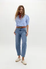 Camisa blanca de algodón con cuello mao, botonera oculta, mangas cortas estilo raglán con cortes estructurados y un bolsillo frontal con cierre.