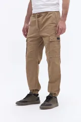 Pantalón cargo de corte relajado color tostado, con cintura elástica y cordón ajustable, bolsillos laterales tipo cargo y puños elásticos en los tobillos.