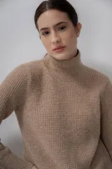 Polera gris de tejido de punto grueso, con cuello alto y mangas largas.