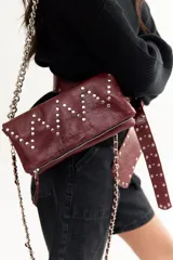 Bandolera de cuero negra con diseño en zigzag de tachas plateadas y asa de cadena metálica.