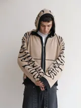 Hoodie con cierre frontal, confeccionado en tejido de punto 100% algodón. Es una prenda reversible con diseño de estampado gráfico en mangas y capucha, y presenta detalles de roturas intencionales en puños, ruedo y bolsillos.