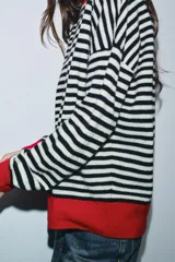 Jersey de lana 100% con rayas horizontales rojas y blancas, cuello redondo y puños y dobladillo en color marrón.