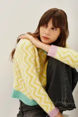 Sweater de punto con diseño de zigzag en tonos amarillo y blanco, cuello redondo, puños en color lila y ruedo en color verde menta.