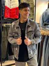 Campera de jean gris con efecto lavado y roturas. Tiene cuello clásico, cierre con botones metálicos, bolsillos en el pecho y laterales.