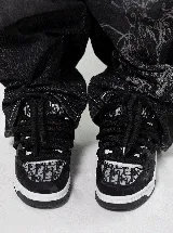 Championes estilo skate de diseño robusto y ancho, con paneles estampados con monograma y detalles en negro. Presentan cordones gruesos tipo chunky y suela de goma blanca y negra.
