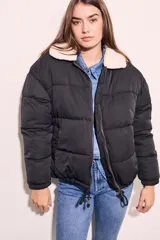 Campera puffer negra con cuello de corderito color crema, cierre frontal con cremallera y cordón ajustable en el ruedo.