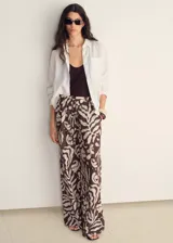 Pantalon de corte recto y tiro medio, con cintura elástica y cordón ajustable. Presenta un estampado abstracto de hojas en tonos marrones y crema, y cuenta con dos bolsillos laterales.