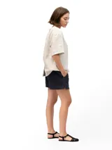 Remera de lino con corte holgado, cuello redondo y mangas cortas. Presenta un diseño minimalista con detalle de botones en la espalda.