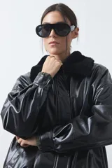 Campera de cuero sintético con acabado satinado, silueta relajada y elástico en la cintura. Presenta cuello con textura de piel sintética, cierre frontal y bolsillos laterales.