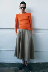 Falda midi de tiro medio con diseño evasé, confeccionada en tejido con viscosa y acabado tipo espiga. Cuenta con cierre de cremallera oculta en el lateral.