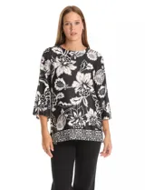 Blusa de seda fría con estampado floral en blanco y negro. Presenta cuello a la base, mangas tres cuartos amplias y ruedo con abertura lateral decorada con botones.