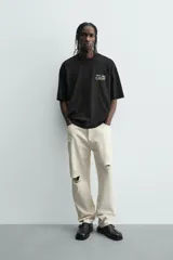 Camiseta negra de corte boxy fit, cuello redondo y manga corta, con estampado frontal en blanco y amarillo que dice "Social Media & Ciao Amore".