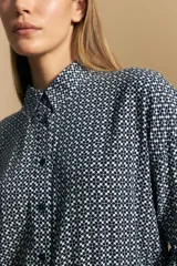 Camisa de manga larga con diseño de rayas verticales en tonos grises y blancos, cuello camisero y cierre frontal con botones.