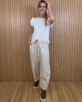 Pantalón de lino color beige, de corte barrel y tiro medio, con cintura elástica ajustable con cordón y bolsillos laterales.