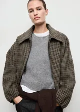 Chaqueta bomber de mezcla de lana con diseño de pata de gallo en tonos marrones y verdes, cuello camisero, manga larga con puños elásticos y bajo elástico. Cuenta con forro interior y cierre delantero con cremallera.