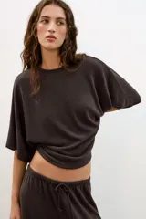 Top blanco de tejido rústico, con cuello redondo y mangas cortas amplias. Bajo recto.