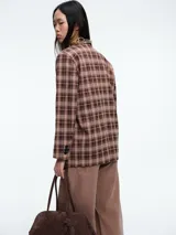 Blazer de corte estructurado con estampado de cuadros en tonos marrones. Presenta solapas clásicas, cierre frontal de un botón y mangas largas.