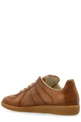 Championes Maison Margiela modelo Replica con efecto desgastado, confeccionados en cuero color marrón, cordones blancos y suela de goma tipo trampa.