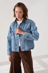 Campera de jean de corte regular estilo camisera, con cuello de pana en color marrón, cierre frontal con botones metálicos dorados y bolsillos frontales con solapa.