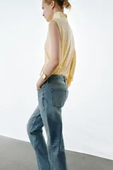 Jeans de tiro medio con corte slim y largo completo. Presentan diseño de cinco bolsillos, cierre frontal con cremallera y botón, efecto lavado y detalle de rotura en la parte delantera con bajo sin costura.